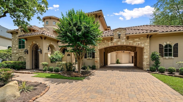 10 Maroon Creek Ct, Spring, TX 77389 - mediterranean / spanish-style house featuring decorative driveway, a tile roof, stucco siding, stone siding, and a garage