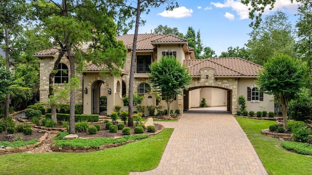 10 Maroon Creek Ct, Spring, TX 77389 - mediterranean / spanish-style home featuring a tiled roof, stucco siding, decorative driveway, a front lawn, and a balcony