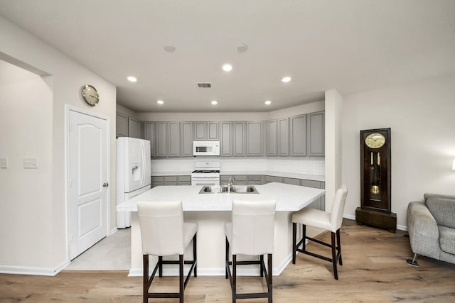 13003 Mills Creek Meadow Dr, Houston, TX 77070 - kitchen featuring white appliances, gray cabinets, a sink, an island with sink, and recessed lighting