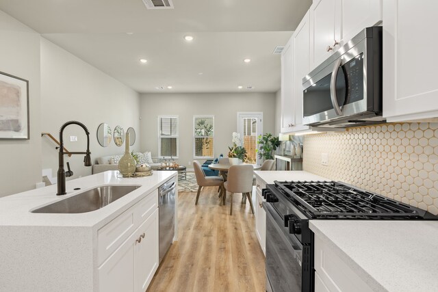 5811 Francis Oak Pl, Houston, TX 77091 - kitchen featuring appliances with stainless steel finishes, light wood-style flooring, white cabinetry, tasteful backsplash, and recessed lighting
