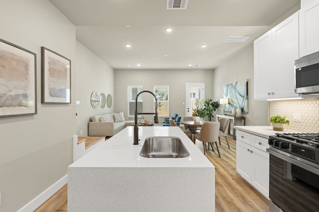 5811 Francis Oak Pl, Houston, TX 77091 - kitchen featuring appliances with stainless steel finishes, light wood-style floors, backsplash, white cabinetry, and recessed lighting