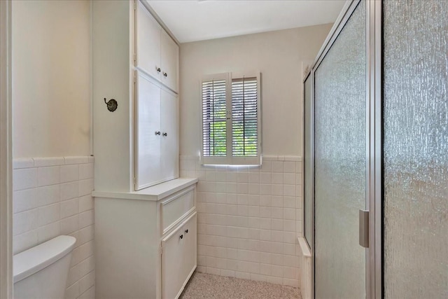 1705 E Texas Ave, Baytown, TX 77520 - bathroom featuring tile walls, toilet, a wainscoted wall, and a stall shower