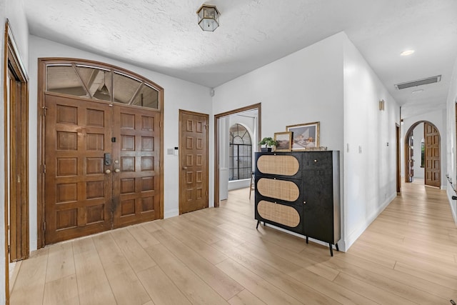 1915 Morton League Rd, Richmond, TX 77406 - foyer entrance featuring arched walkways, light wood-style floors, baseboards, and a textured ceiling