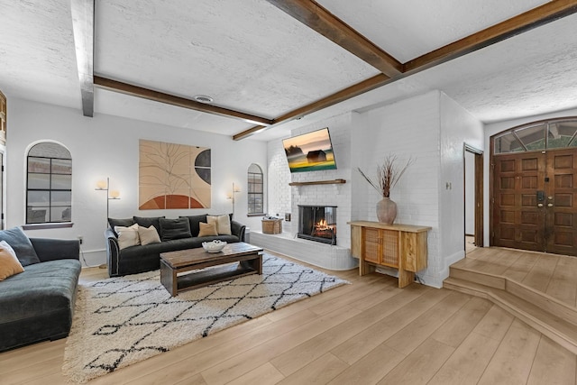 1915 Morton League Rd, Richmond, TX 77406 - living area featuring wood finished floors, beamed ceiling, a textured ceiling, and a brick fireplace