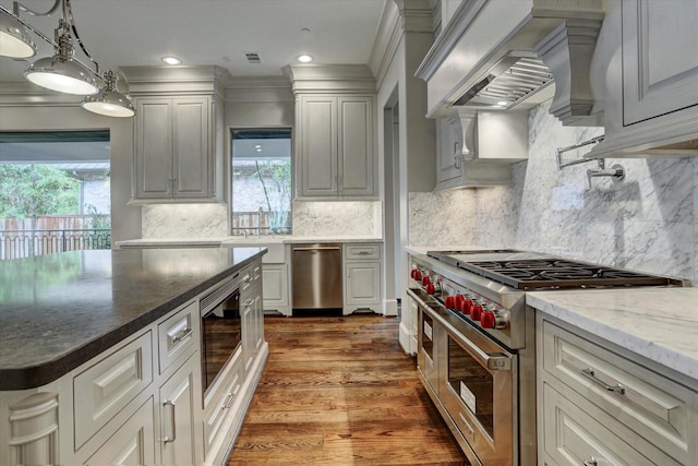 8304 Maple Ct, Bellaire, TX 77401 - kitchen with appliances with stainless steel finishes, plenty of natural light, wood finished floors, custom exhaust hood, and recessed lighting