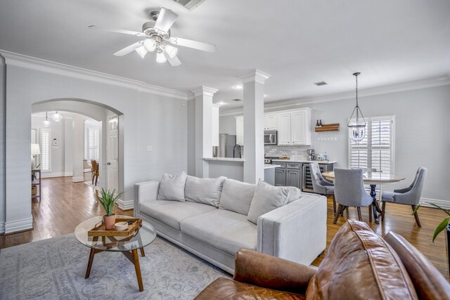 1441 W 25th St Unit D, Houston, TX 77008 - living room featuring a ceiling fan, ornamental molding, baseboards, wood finished floors, and arched walkways