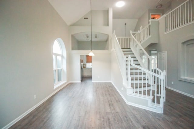 10407 Redwood Dr, Baytown, TX 77523 - unfurnished living room featuring high vaulted ceiling, stairway, wood finished floors, and baseboards