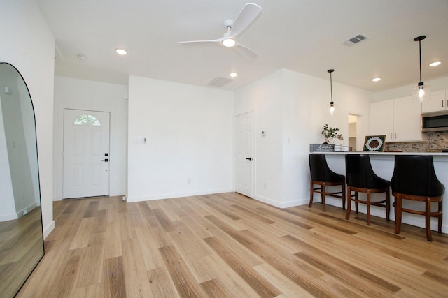 624 Pinewood Dr, Conroe, TX 77385 - kitchen with stainless steel microwave, white cabinetry, hanging light fixtures, ceiling fan, and light wood-style floors