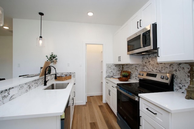 624 Pinewood Dr, Conroe, TX 77385 - kitchen with appliances with stainless steel finishes, a sink, a peninsula, decorative backsplash, and light wood-type flooring