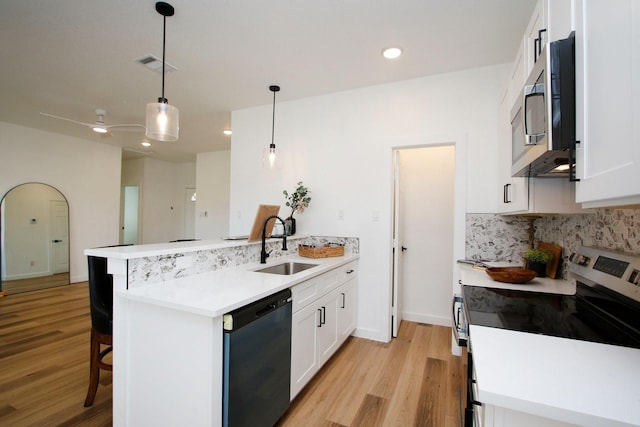 624 Pinewood Dr, Conroe, TX 77385 - kitchen with appliances with stainless steel finishes, a peninsula, a sink, light wood-style flooring, and backsplash