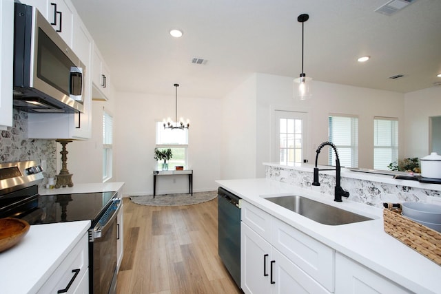 624 Pinewood Dr, Conroe, TX 77385 - kitchen featuring appliances with stainless steel finishes, a sink, backsplash, light wood finished floors, and a chandelier