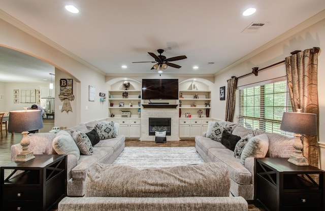 9107 Black Buck Ln, Conroe, TX 77303 - living area featuring ceiling fan, arched walkways, ornamental molding, a fireplace, and recessed lighting