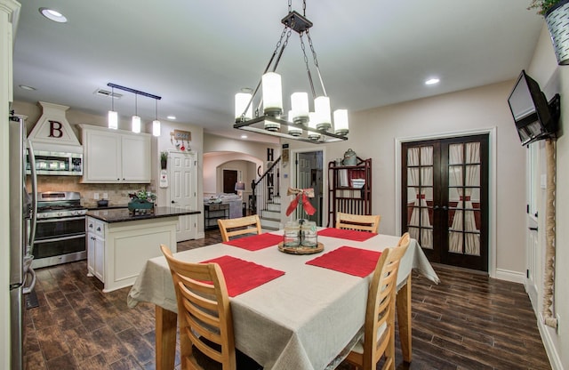 9107 Black Buck Ln, Conroe, TX 77303 - dining space featuring arched walkways, dark wood-type flooring, stairs, a chandelier, and recessed lighting