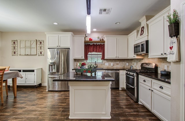 9107 Black Buck Ln, Conroe, TX 77303 - kitchen with appliances with stainless steel finishes, white cabinetry, a kitchen island, dark wood-type flooring, and hanging light fixtures