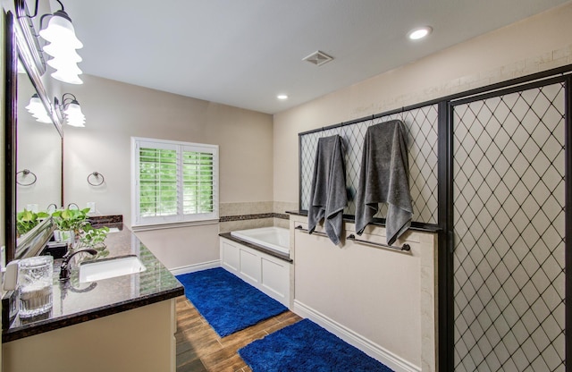 9107 Black Buck Ln, Conroe, TX 77303 - full bathroom featuring vanity, a garden tub, wood finished floors, baseboards, and recessed lighting