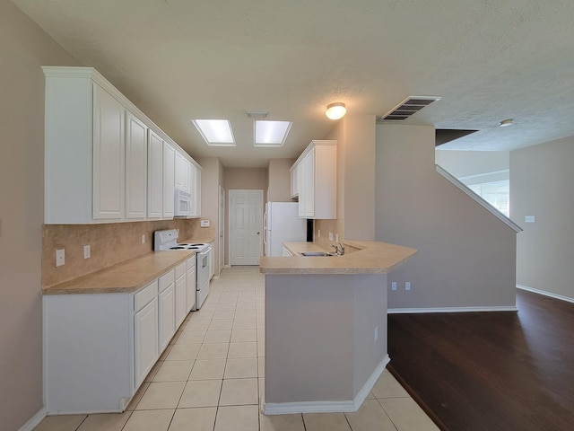 6135 Shelbourne Park Ln, Houston, TX 77084 - kitchen featuring white appliances, baseboards, white cabinetry, light countertops, and a peninsula