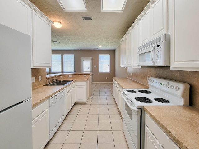 6135 Shelbourne Park Ln, Houston, TX 77084 - kitchen with white appliances, a sink, light tile patterned floors, white cabinetry, and light countertops
