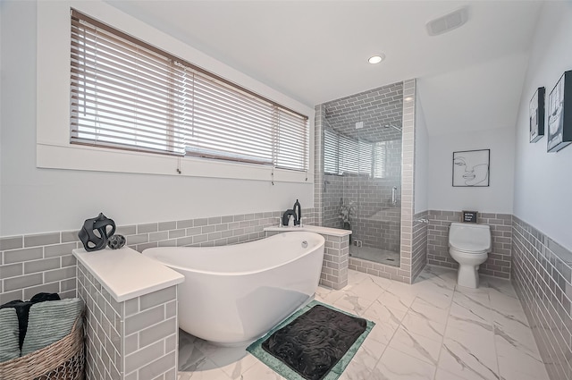206 S Idaho St, La Porte, TX 77571 - bathroom featuring tile walls, healthy amount of natural light, a wainscoted wall, a shower stall, and a freestanding tub