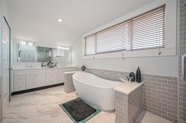 206 S Idaho St, La Porte, TX 77571 - full bath featuring marble look tiles, tile walls, a soaking tub, double vanity, and wainscoting