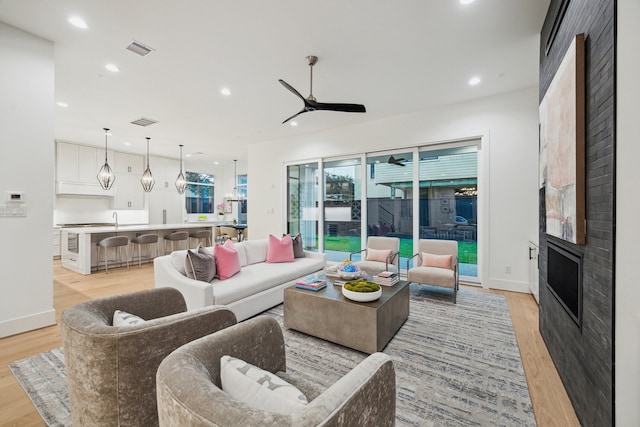 1203 Bomar St, Houston, TX 77006 - living room featuring light wood-style floors, a ceiling fan, a fireplace, recessed lighting, and baseboards