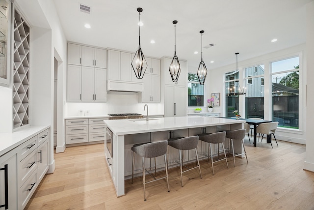 1203 Bomar St, Houston, TX 77006 - kitchen with a sink, light wood-style flooring, light countertops, a breakfast bar, and a center island with sink