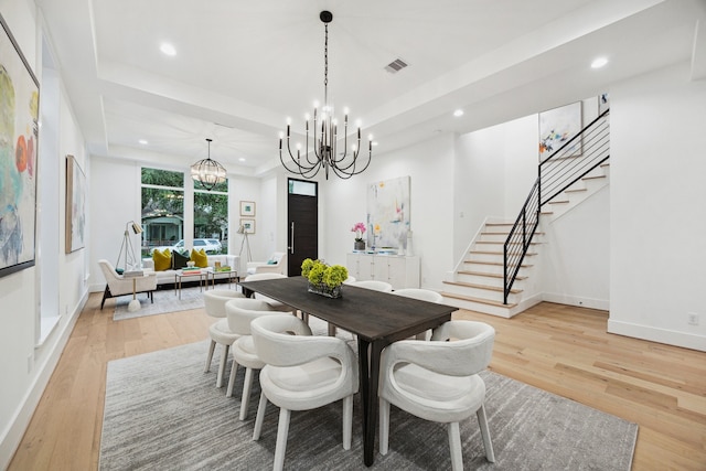 1203 Bomar St, Houston, TX 77006 - dining area with a chandelier, stairway, recessed lighting, light wood-style flooring, and a tray ceiling