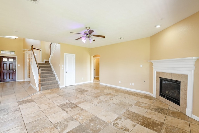 2123 Witham Park Ln, Fresno, TX 77545 - unfurnished living room featuring a ceiling fan, arched walkways, a tile fireplace, baseboards, and stairway