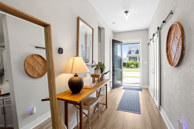 18631 Joyous Ln, Cypress, TX 77433 - entryway featuring a barn door, light wood-style floors, baseboards, and a textured wall