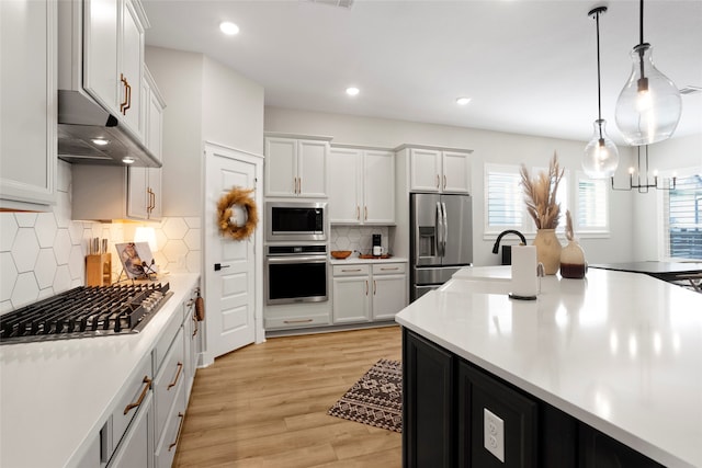 18631 Joyous Ln, Cypress, TX 77433 - kitchen featuring stainless steel appliances, light countertops, recessed lighting, hanging light fixtures, and light wood-style floors