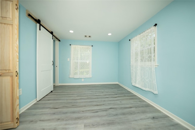 570 Fm 232, Crockett, TX 75835 - unfurnished bedroom featuring a barn door, recessed lighting, baseboards, and light wood finished floors