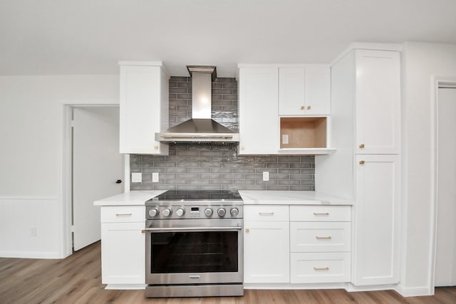 722 Merrick Dr, Sugar Land, TX 77478 - kitchen with stainless steel electric stove, wall chimney exhaust hood, light countertops, white cabinets, and wainscoting