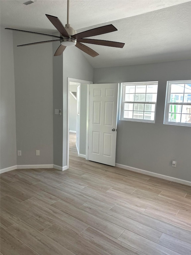 12702 River Bend Dr, Mont Belvieu, TX 77523 - unfurnished room with ceiling fan, a textured ceiling, vaulted ceiling, light wood-style floors, and baseboards
