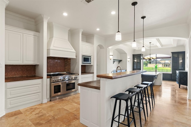 8410 Den Oak Dr, Richmond, TX 77406 - kitchen featuring stainless steel appliances, custom range hood, arched walkways, decorative backsplash, and a large island