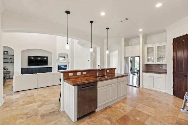 8410 Den Oak Dr, Richmond, TX 77406 - kitchen with appliances with stainless steel finishes, dark countertops, ornamental molding, a center island with sink, and white cabinets