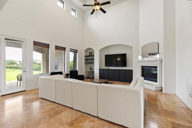 8410 Den Oak Dr, Richmond, TX 77406 - living area featuring built in features, a towering ceiling, ceiling fan, and a glass covered fireplace