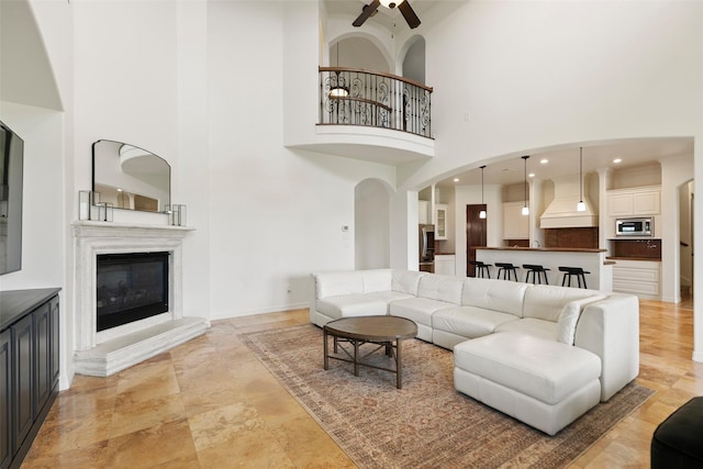 8410 Den Oak Dr, Richmond, TX 77406 - living room with a high ceiling, ceiling fan, a glass covered fireplace, and light stone finish floors