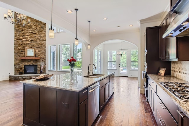 6 Freestone Stream Pl, Spring, TX 77389 - kitchen with a sink, appliances with stainless steel finishes, under cabinet range hood, arched walkways, and dark wood-style floors
