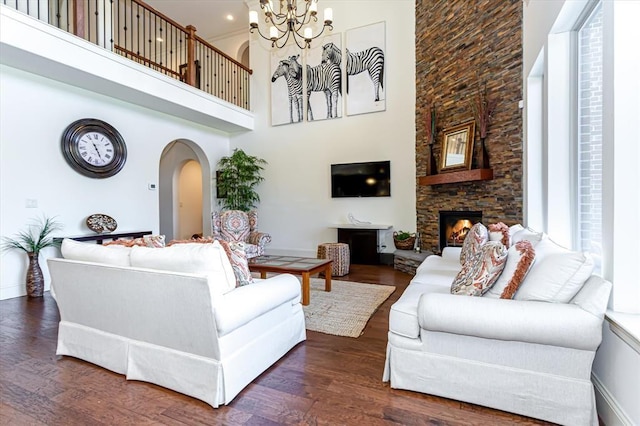 6 Freestone Stream Pl, Spring, TX 77389 - living room featuring arched walkways, a chandelier, dark wood-style flooring, a high ceiling, and a stone fireplace