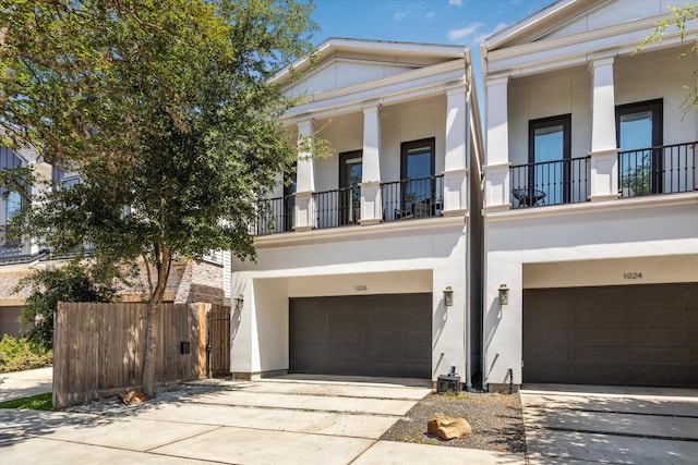 1026 Adele St, Houston, TX 77009 - greek revival house with an attached garage, stucco siding, driveway, and a balcony
