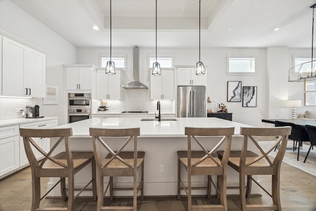 1026 Adele St, Houston, TX 77009 - kitchen featuring stainless steel appliances, wall chimney exhaust hood, a sink, backsplash, and wood finished floors