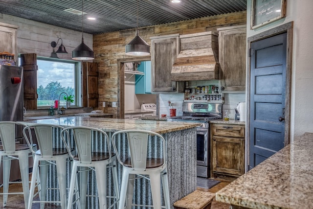1850 Lcr 439, Groesbeck, TX 76667 - kitchen featuring stainless steel gas stove, light stone counters, a breakfast bar area, hanging light fixtures, and wooden walls