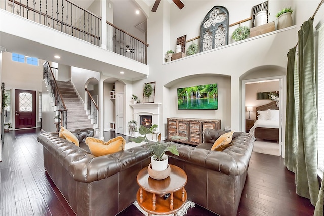 2610 Cedar Path Ln, Conroe, TX 77385 - living area with a high ceiling, ceiling fan, a lit fireplace, dark wood-style flooring, and stairway