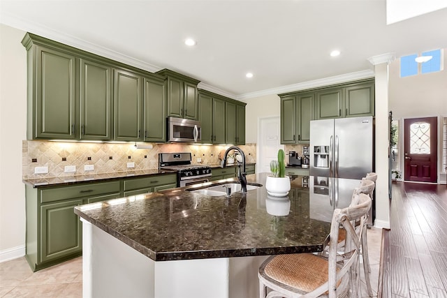 2610 Cedar Path Ln, Conroe, TX 77385 - kitchen featuring appliances with stainless steel finishes, green cabinetry, a sink, a kitchen bar, and crown molding