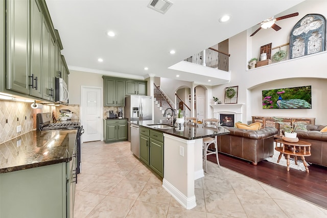 2610 Cedar Path Ln, Conroe, TX 77385 - kitchen with green cabinets, a sink, appliances with stainless steel finishes, open floor plan, and ornamental molding