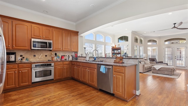 18725 Egret Oaks Ln, Webster, TX 77058 - kitchen with stainless steel appliances, crown molding, a peninsula, a sink, and light wood-type flooring
