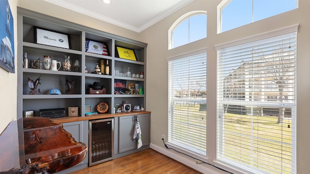 18725 Egret Oaks Ln, Webster, TX 77058 - indoor dry bar featuring beverage cooler, ornamental molding, light wood-style flooring, and baseboards