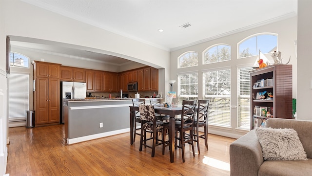 18725 Egret Oaks Ln, Webster, TX 77058 - dining area featuring healthy amount of natural light, crown molding, light wood-style flooring, arched walkways, and recessed lighting
