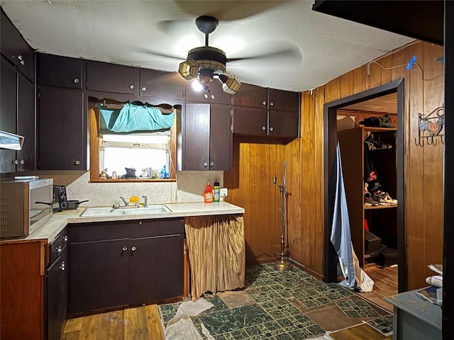 1509 Harry St, Victoria, TX 77901 - kitchen featuring stainless steel microwave, a sink, a ceiling fan, light countertops, and wood walls