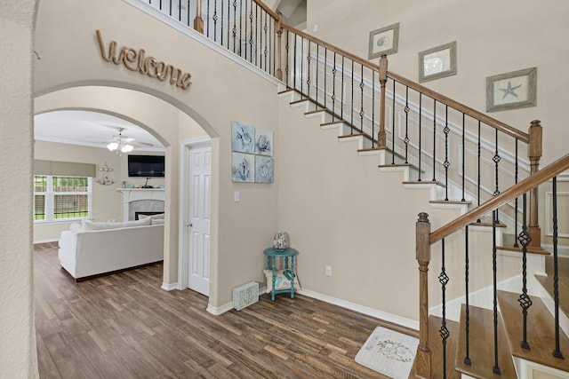 3518 Bain St, Houston, TX 77026 - staircase featuring ceiling fan, wood finished floors, arched walkways, a fireplace, and baseboards