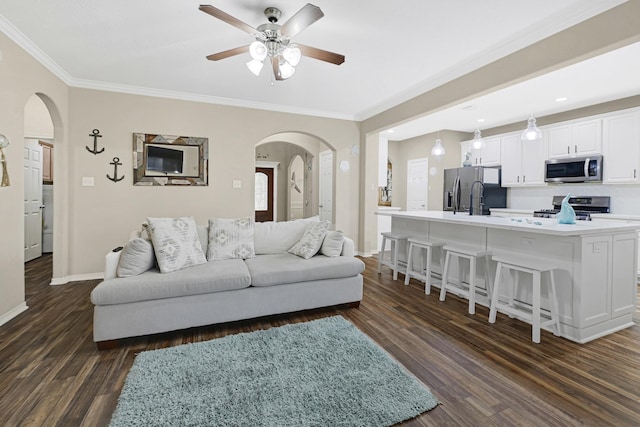 3518 Bain St, Houston, TX 77026 - living area with arched walkways, dark wood-type flooring, baseboards, ceiling fan, and crown molding